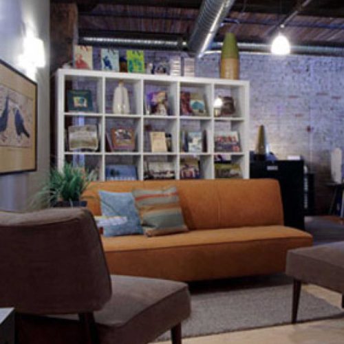 studio sitting area, couch, chairs and shelf with print / design items on display